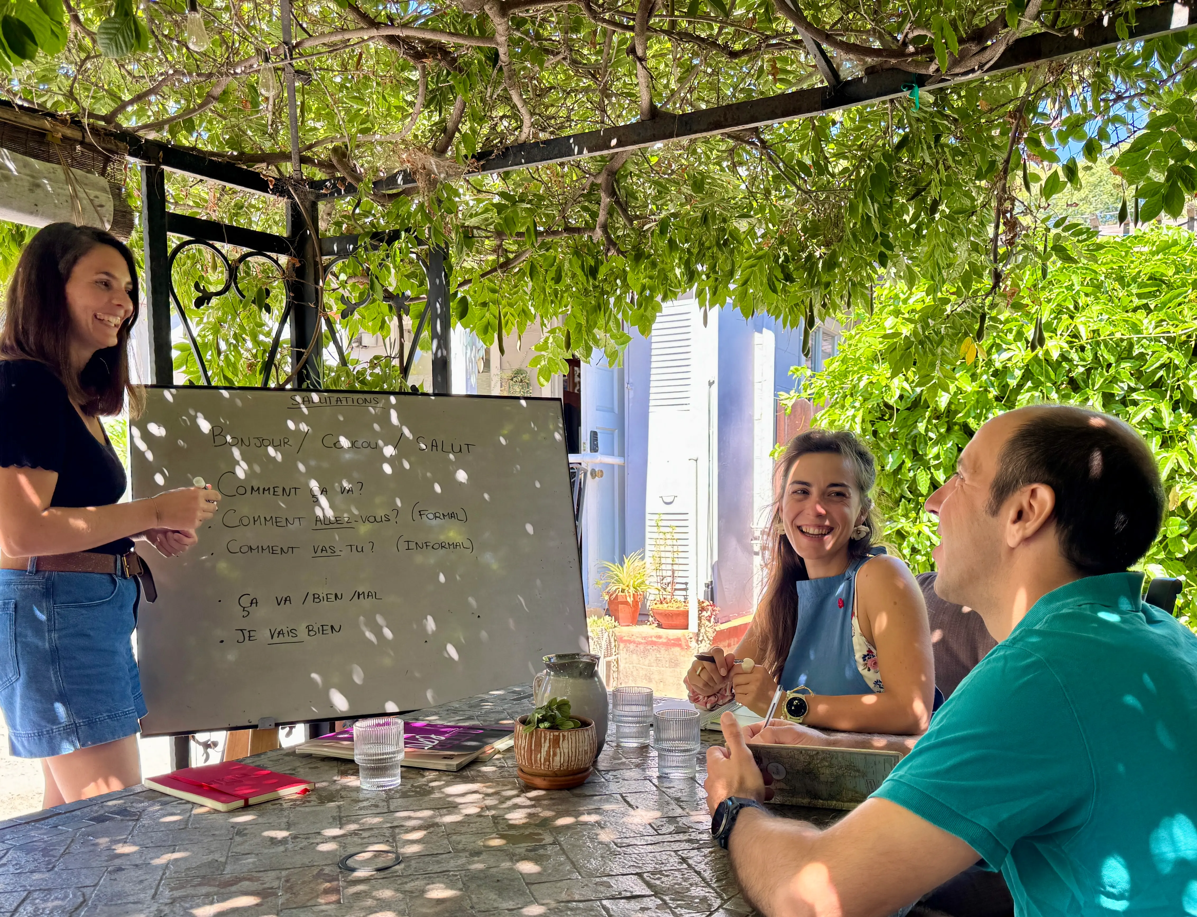 Wanda teaching a small group class at the whiteboard under a garden pergola