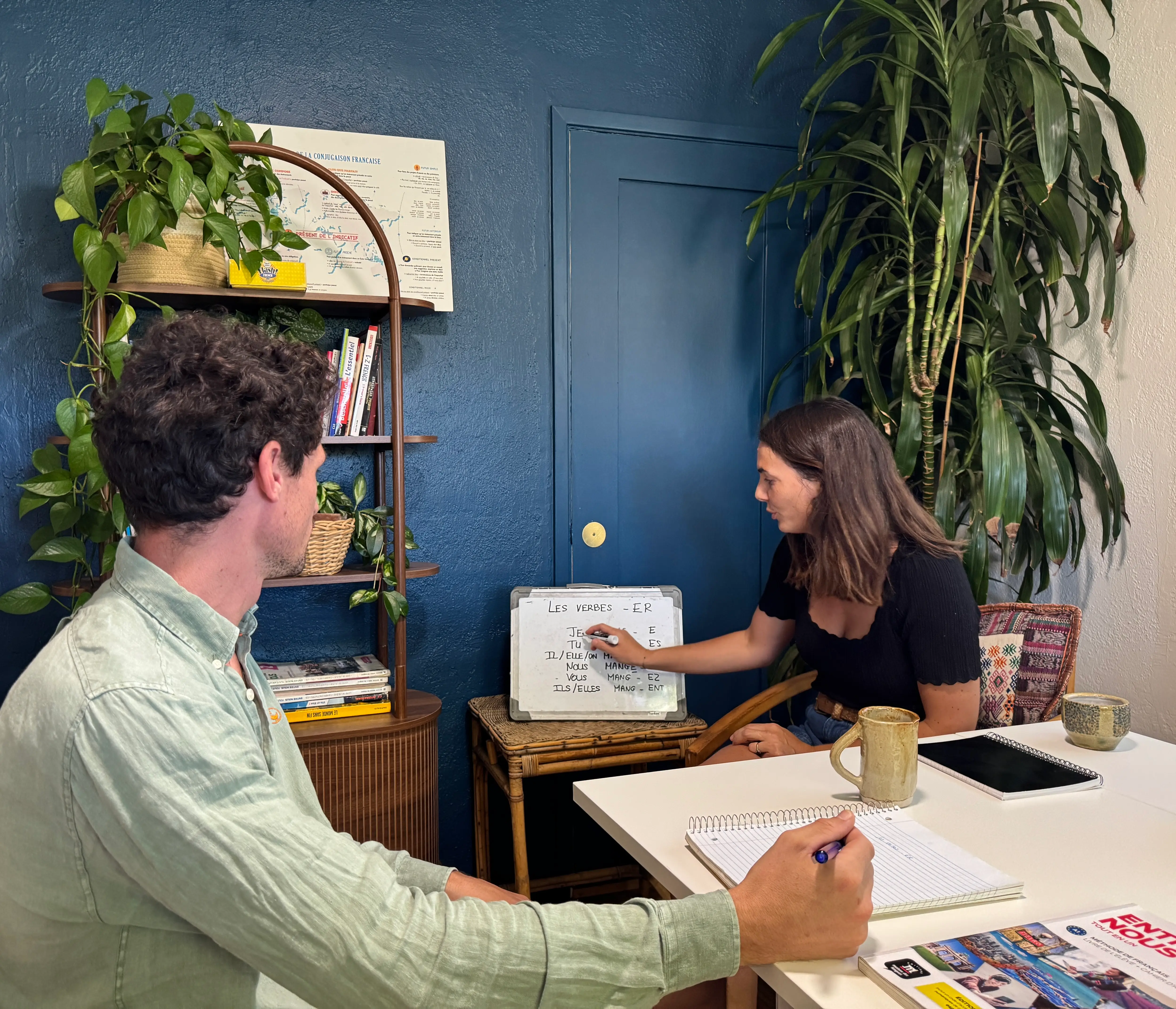 A one-on-one French lesson at the whiteboard, conjugating -er verbs